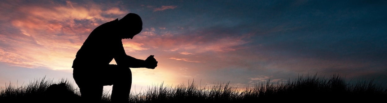 Man Praying In The Grassy Field