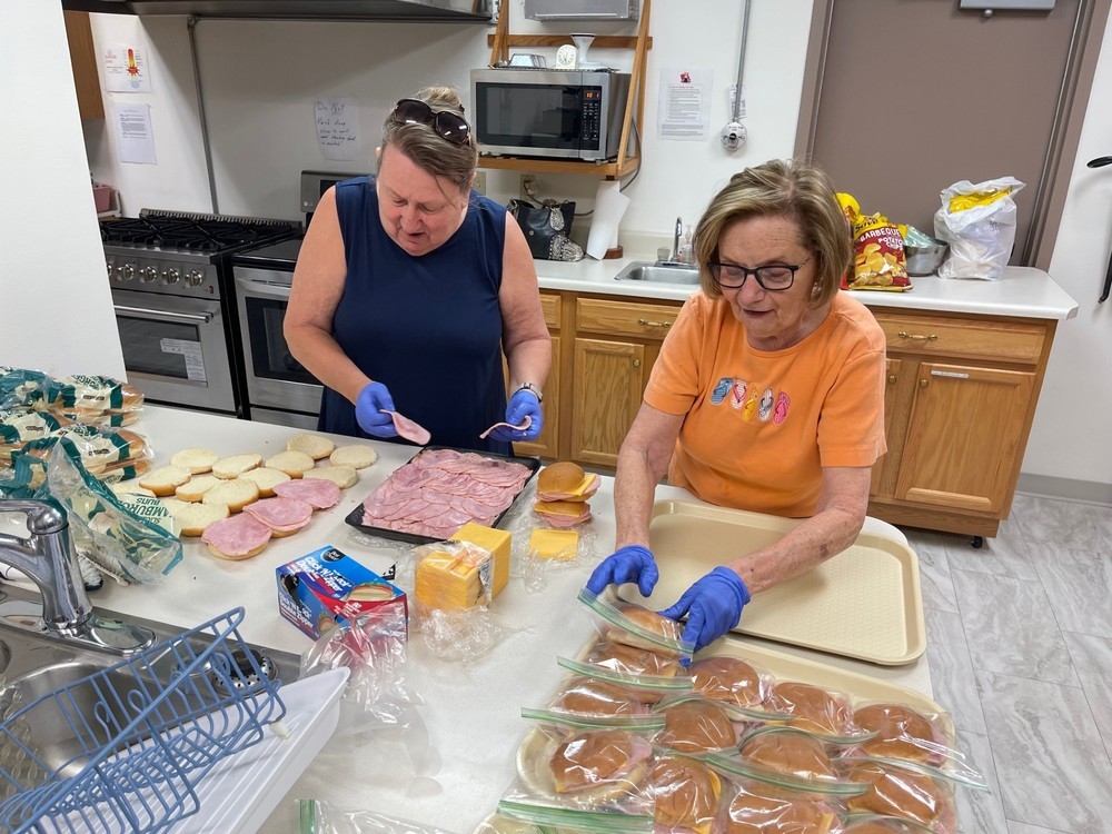 Two women prepare sandwiches